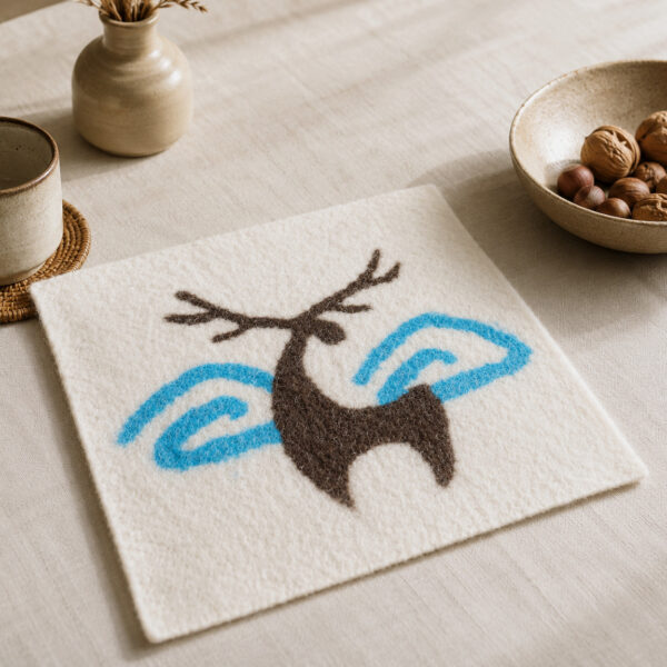Carré écru à motif de cerf brun et formes bleues sur une table