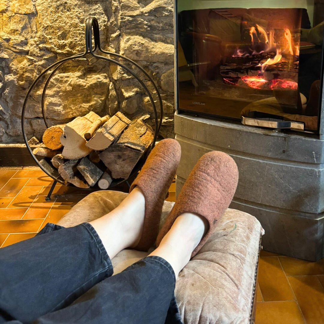 Chaussons en laine feutrée devant une cheminée