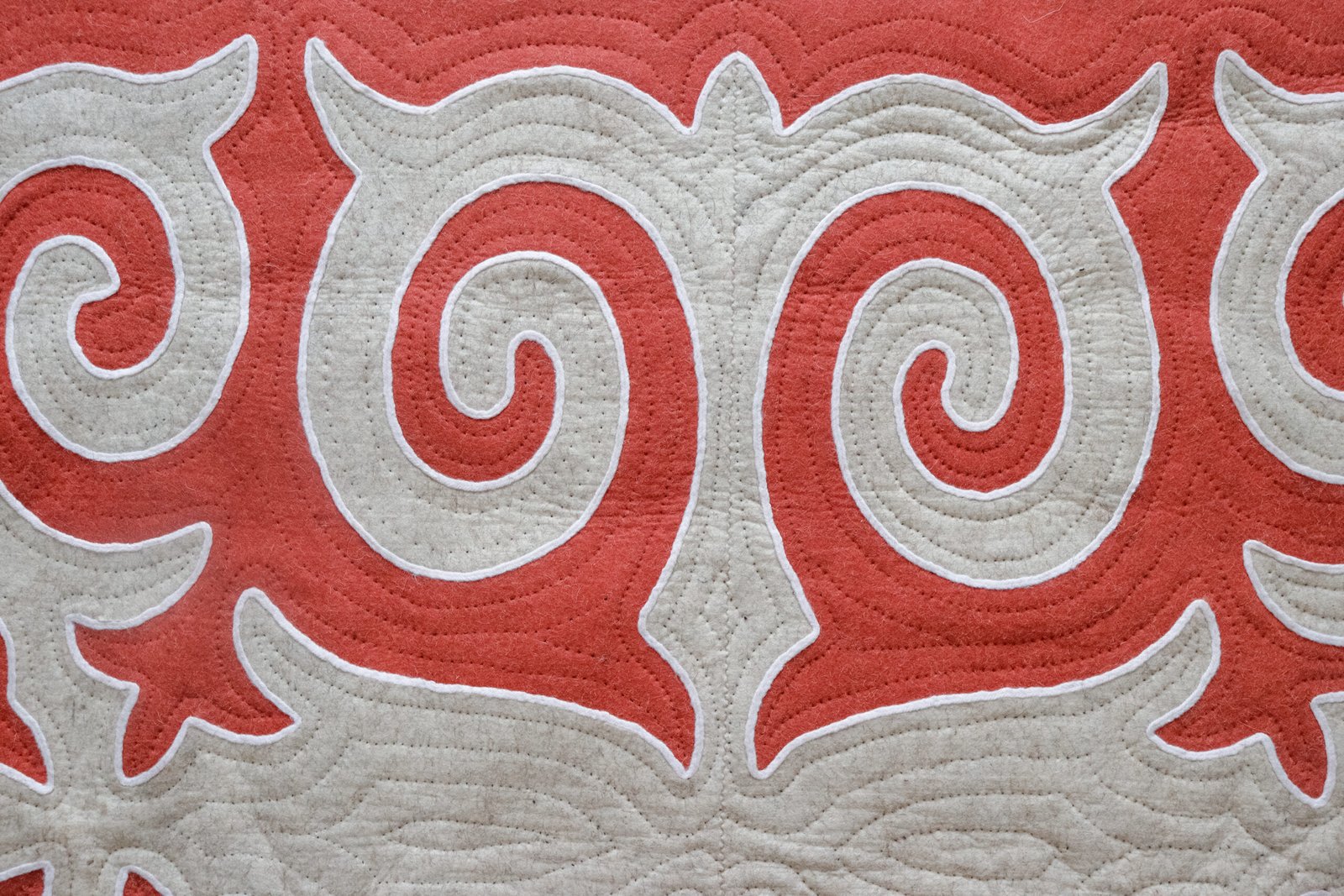 Détail des motifs bleu foncé et ivoire et des coutures d’un Shyrdak