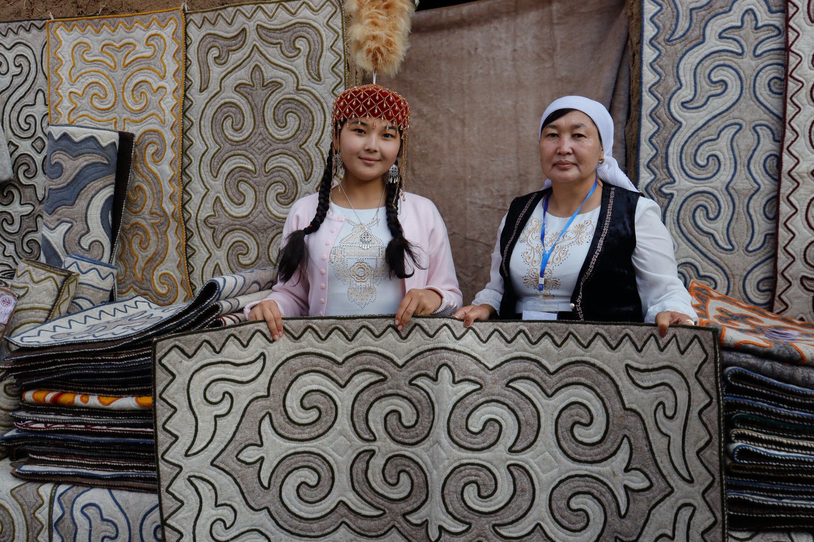 Trois femmes assises sur des tapis Shyrdak colorés
